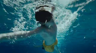 a man swimming in a pool with a surfboard