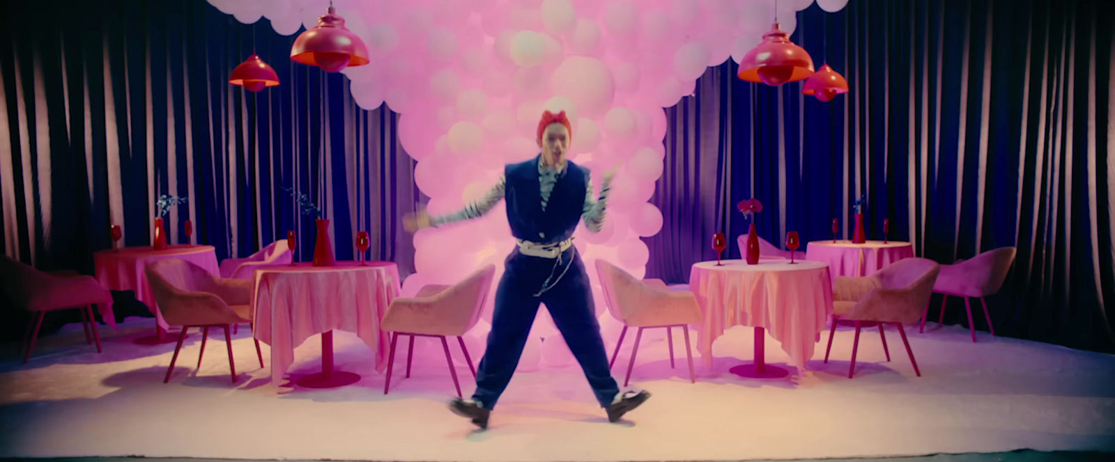 a man is dancing in front of a pink backdrop