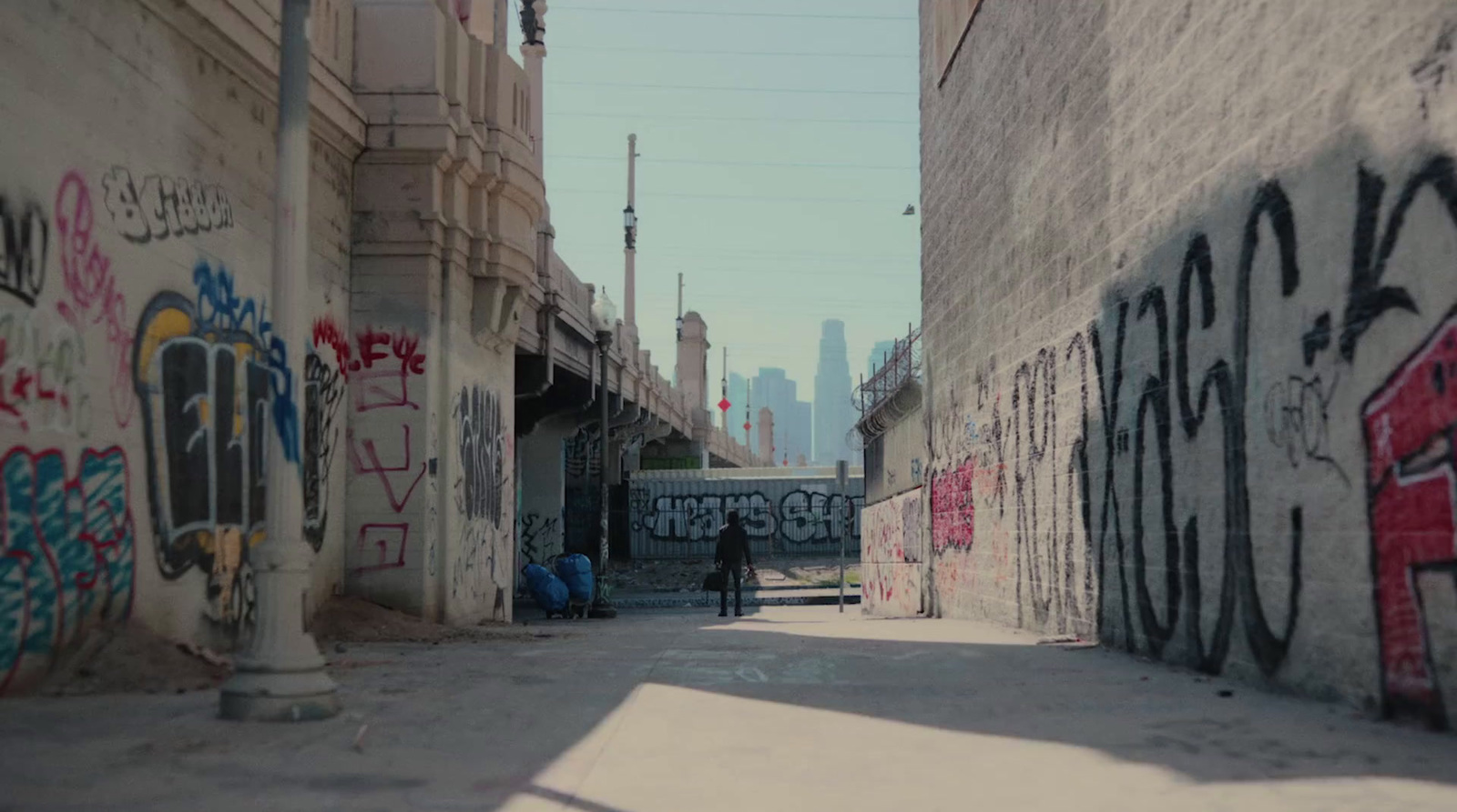 a person standing in an alley with graffiti on the walls