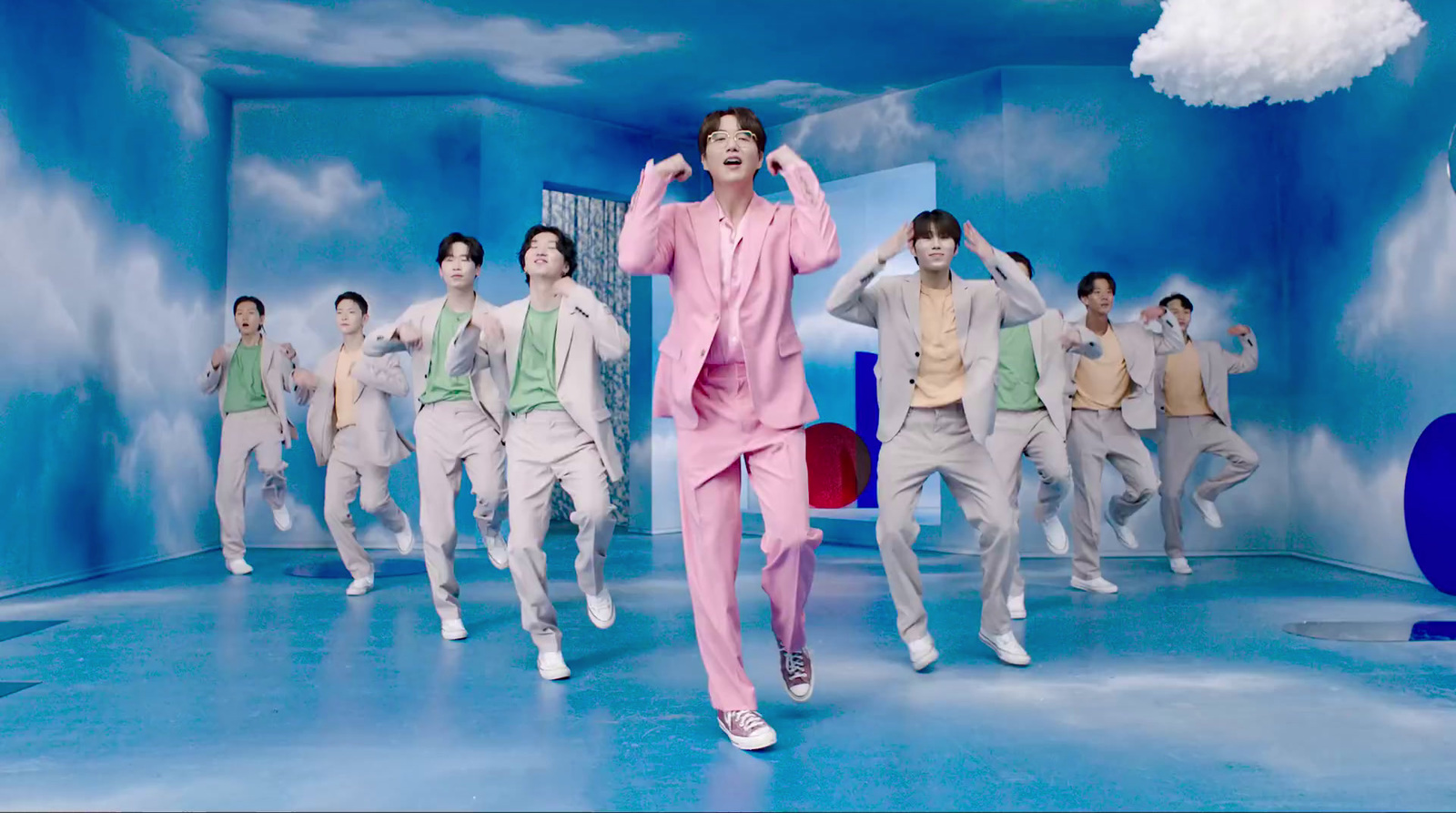 a man in a pink suit dancing in front of a group of people