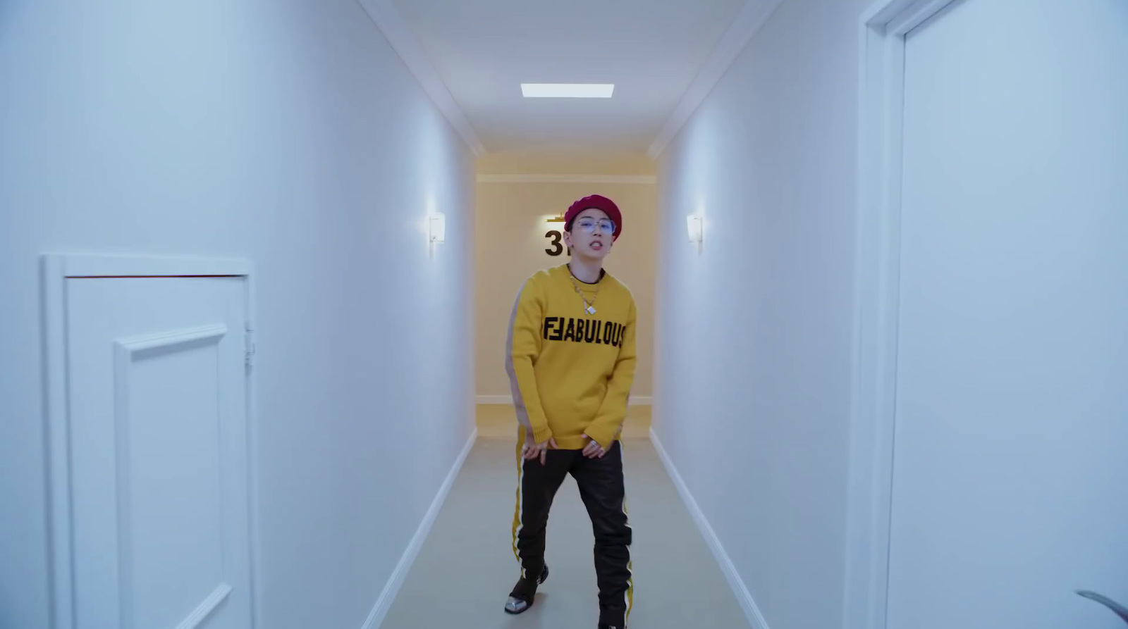 a man in a yellow sweater standing in a hallway