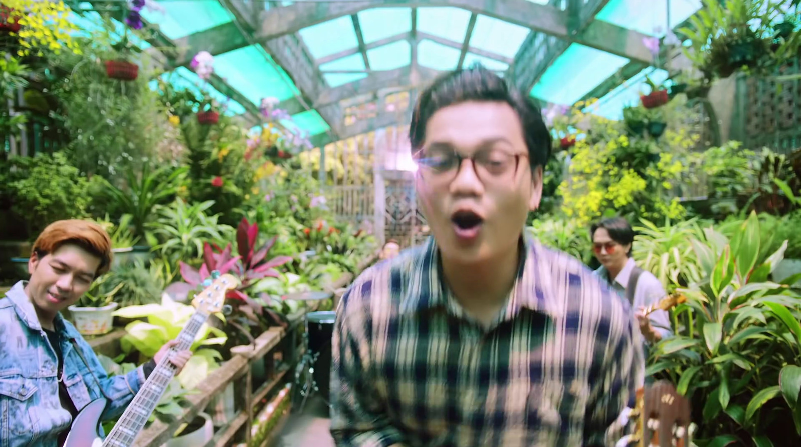 a man standing in a greenhouse holding a guitar