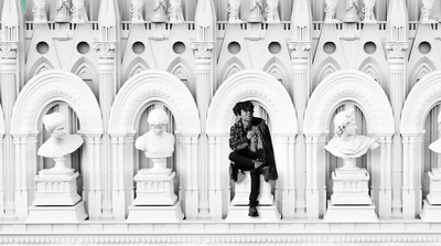 a person sitting on a ledge in front of a building