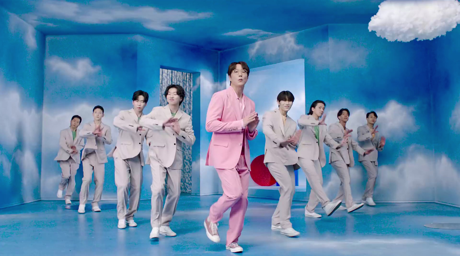 a man in a pink suit standing in front of a group of other men