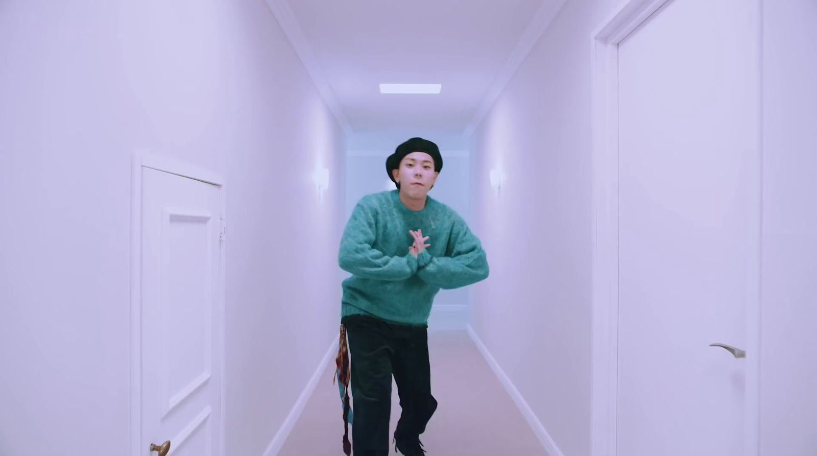 a man in a green sweater standing in a hallway