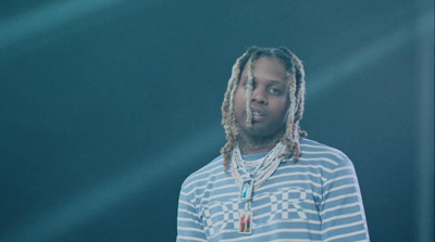 a man with dreadlocks standing in front of a black background