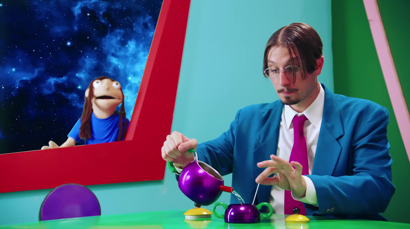 a man sitting at a table with a purple teapot