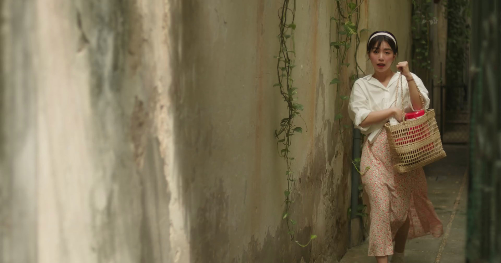 a woman walking down a street carrying a basket