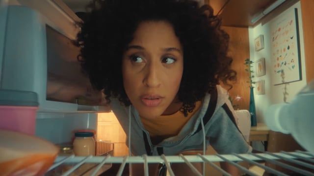 a woman looking into an open refrigerator