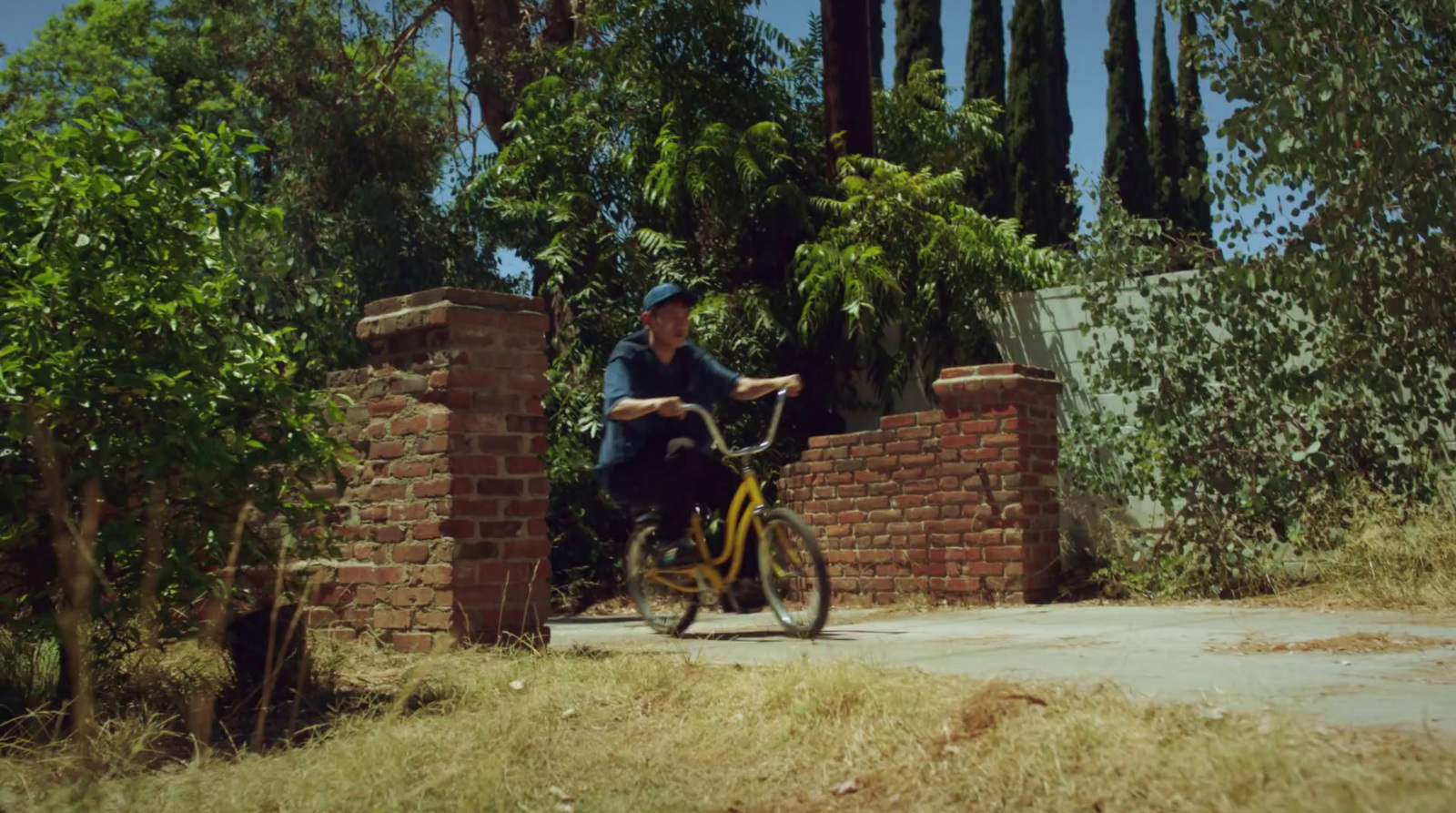 a man riding a bike down a street next to a brick wall