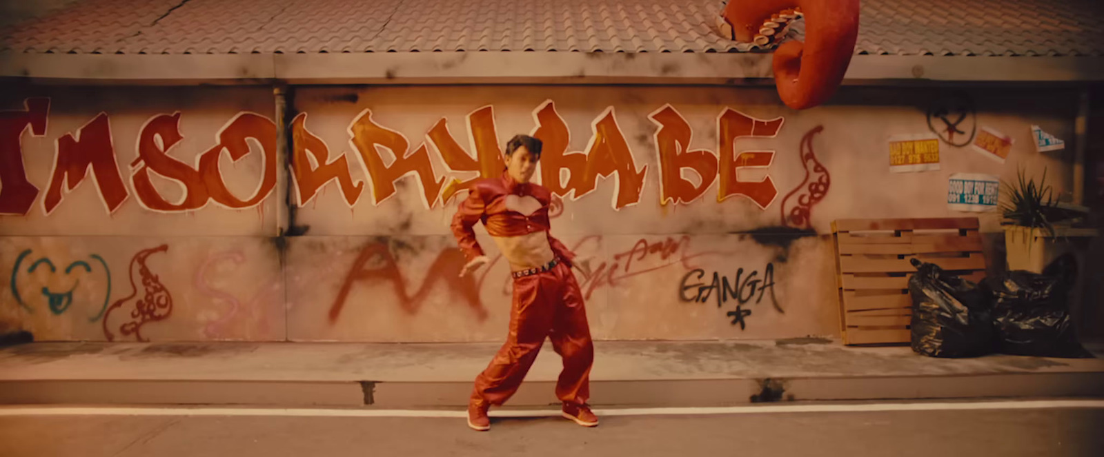 a man in a clown suit standing in front of a graffiti covered wall