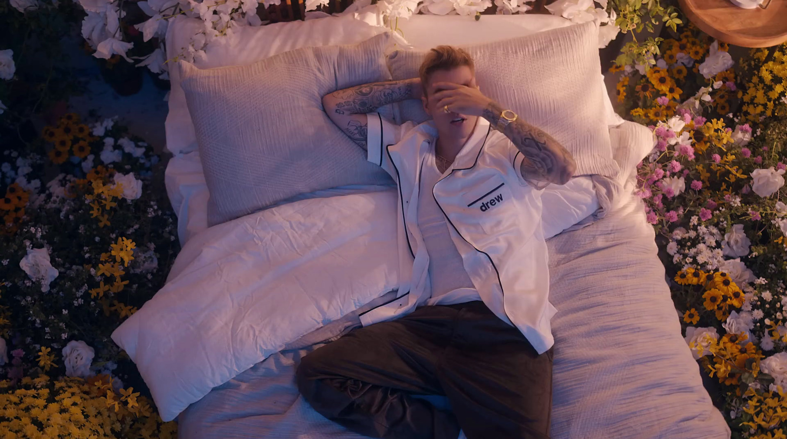 a man laying on a bed covered in lots of flowers