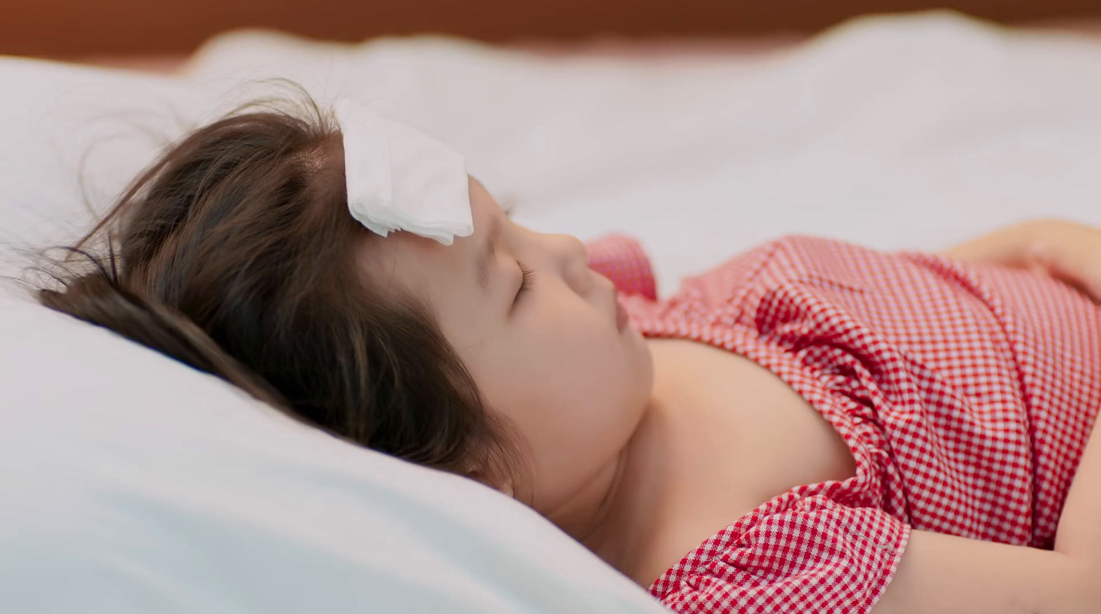 a little girl laying on a bed with a pillow