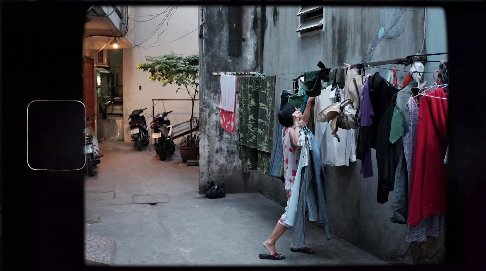 a woman standing next to a wall with clothes hanging on it