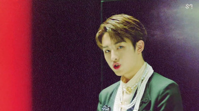 a young man in a green jacket and pearl necklace