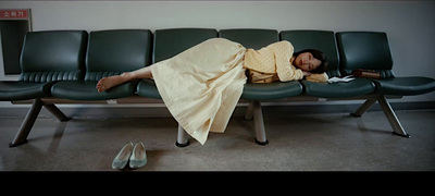 a woman laying on a bench with a blanket over her head