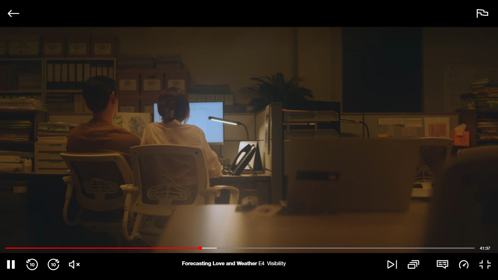 a man and a woman sitting at a desk in front of a computer