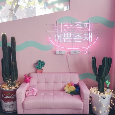 a pink couch in a room with a neon sign above it