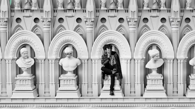 a black and white photo of a man sitting on a wall