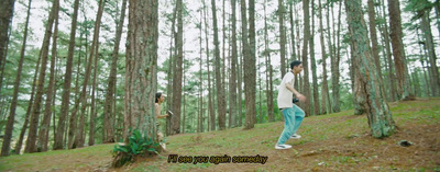 a man and a woman walking through a forest