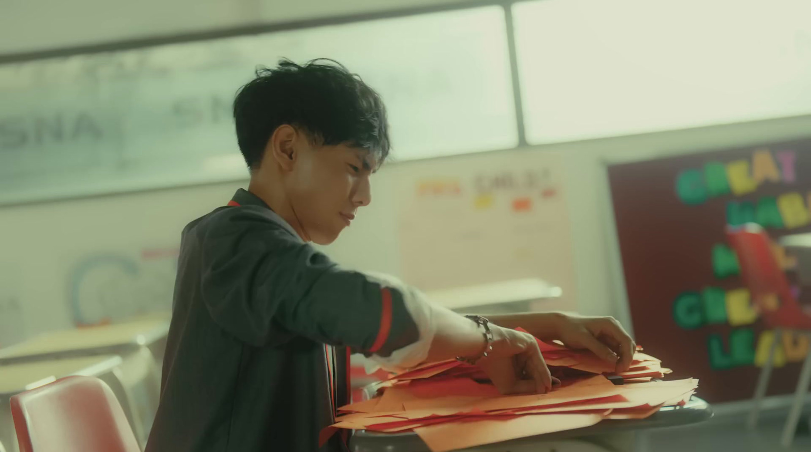 a young man sitting at a desk with a pile of papers