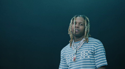 a man with dreadlocks standing in front of a black background