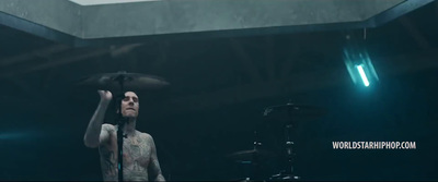 a man with tattoos holding a drum in front of a microphone