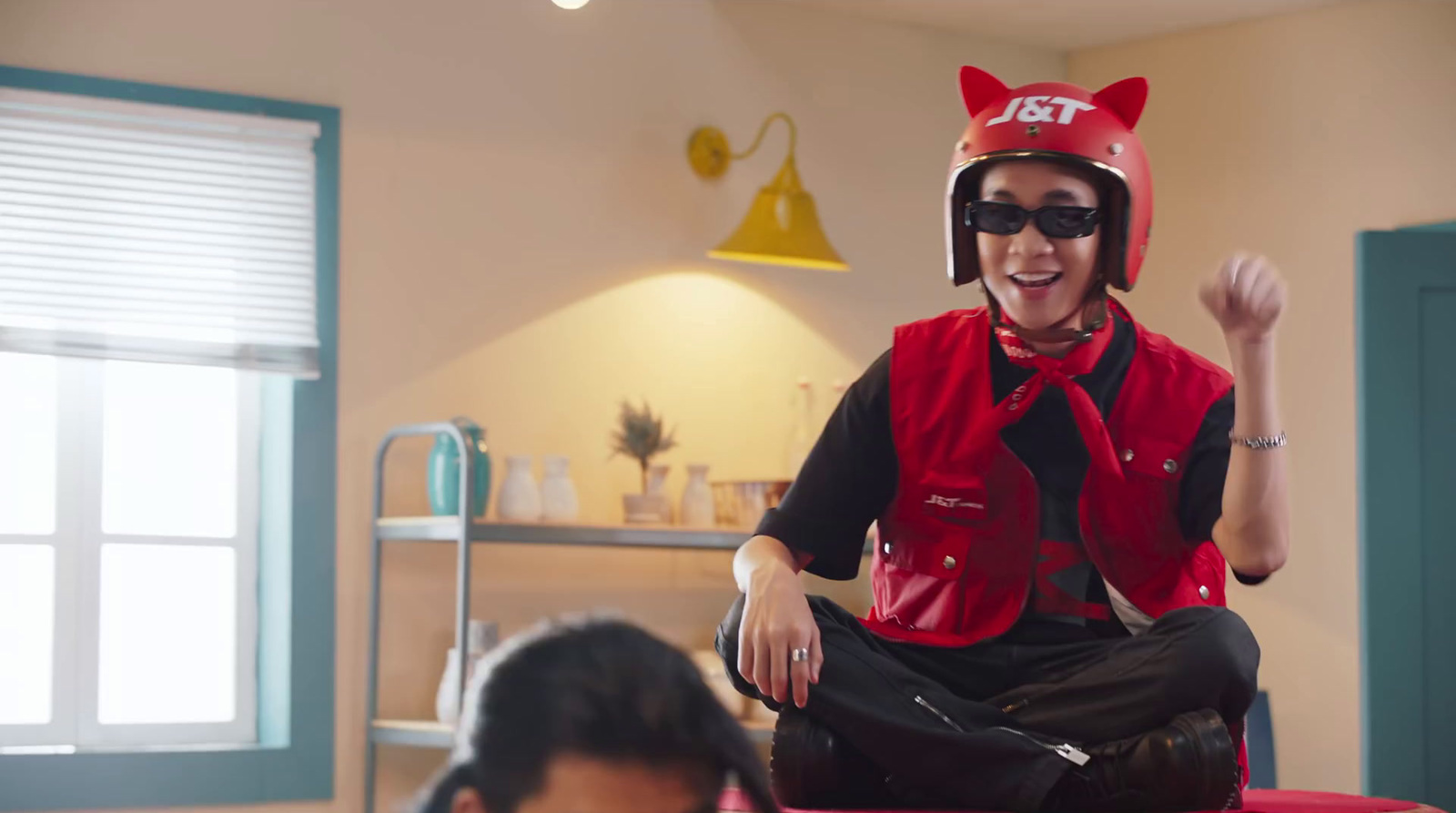 a man in a cat mask sitting on a stool