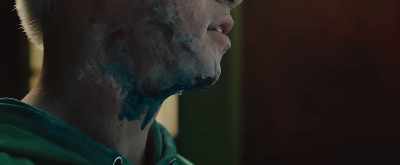 a man in a green hoodie covered in blue paint