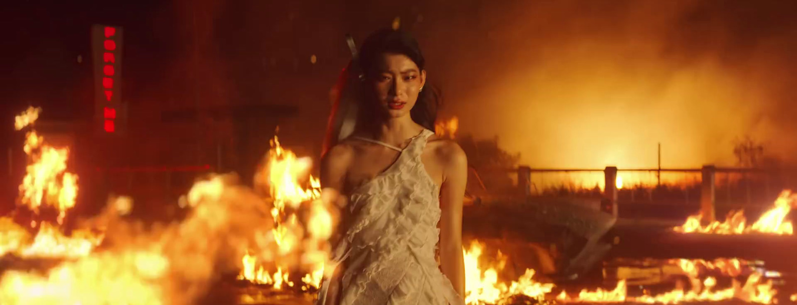 a woman in a white dress standing in front of a fire