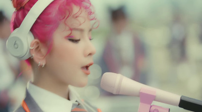 a woman with pink hair is singing into a microphone