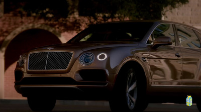 a brown bentley suv parked in front of a building