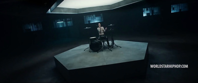 a man standing on top of a stage next to a drum set