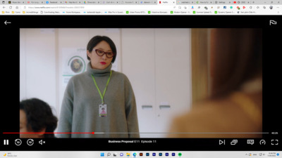 a woman in a gray sweater and glasses standing in front of a mirror