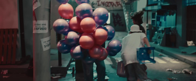 a woman walking down a street with a bunch of balloons