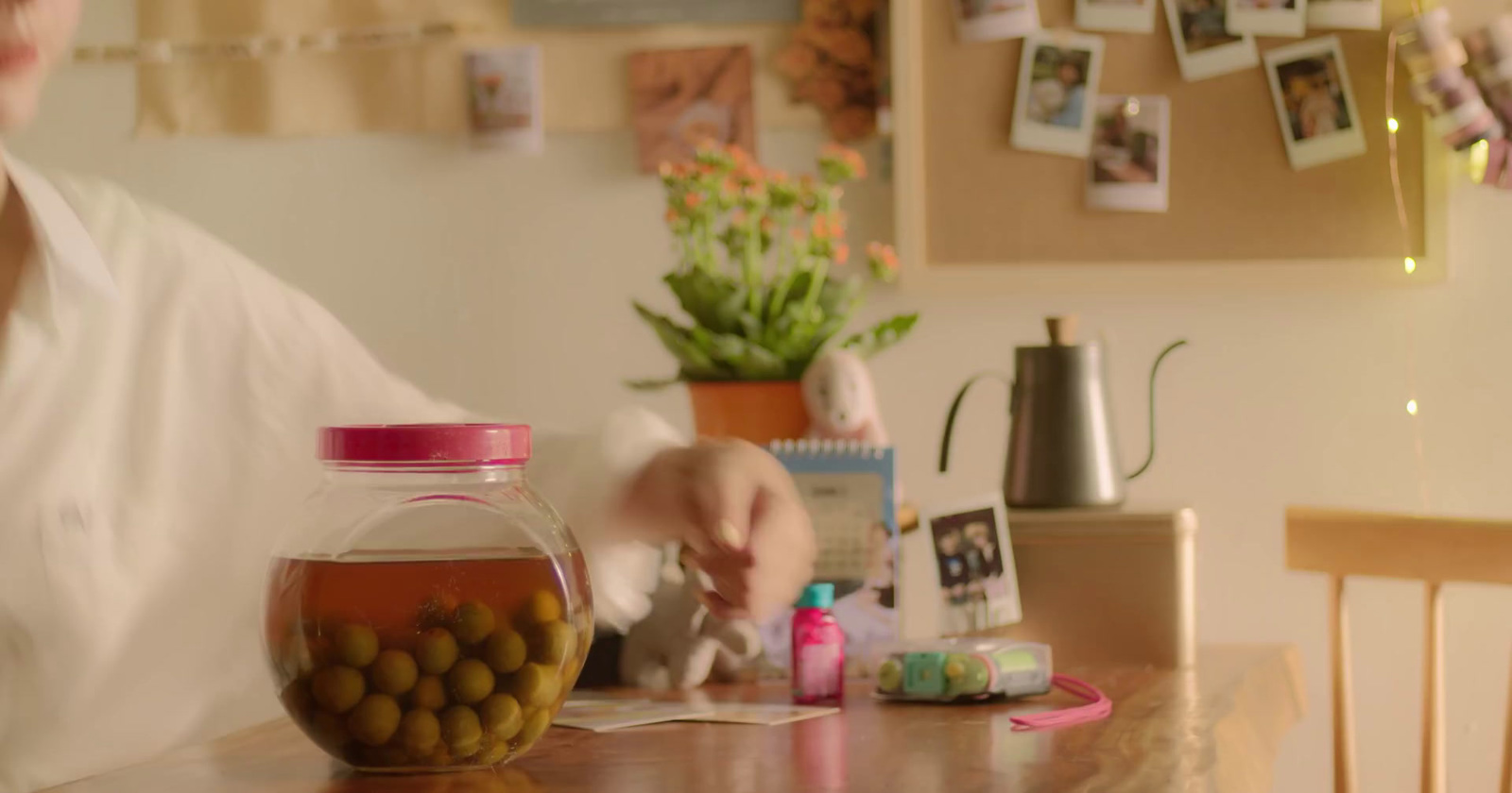 a woman sitting at a table with a jar of olives