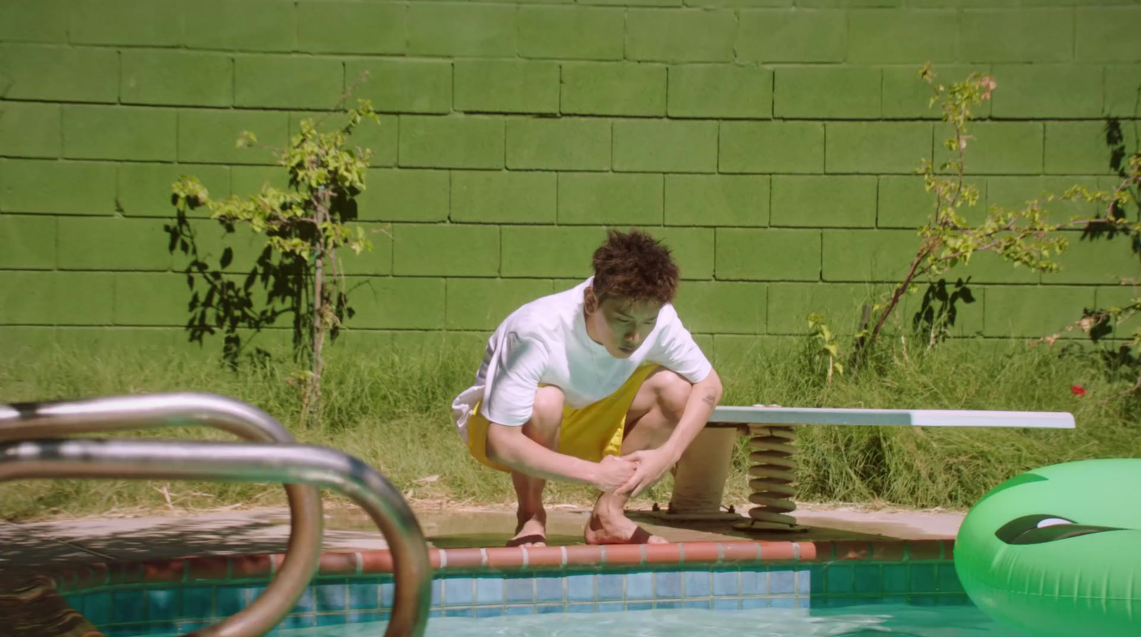 a man sitting on the edge of a swimming pool