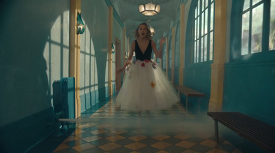 a woman in a white dress walking down a hallway