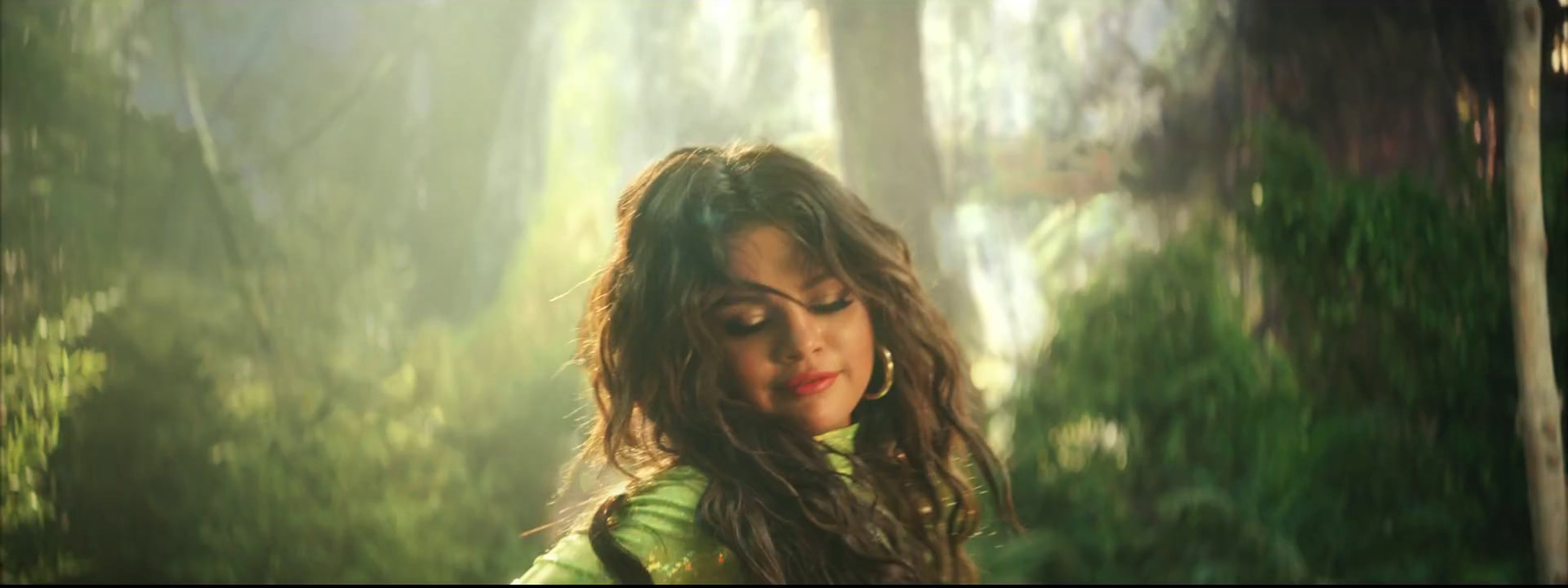 a woman with long hair standing in a forest