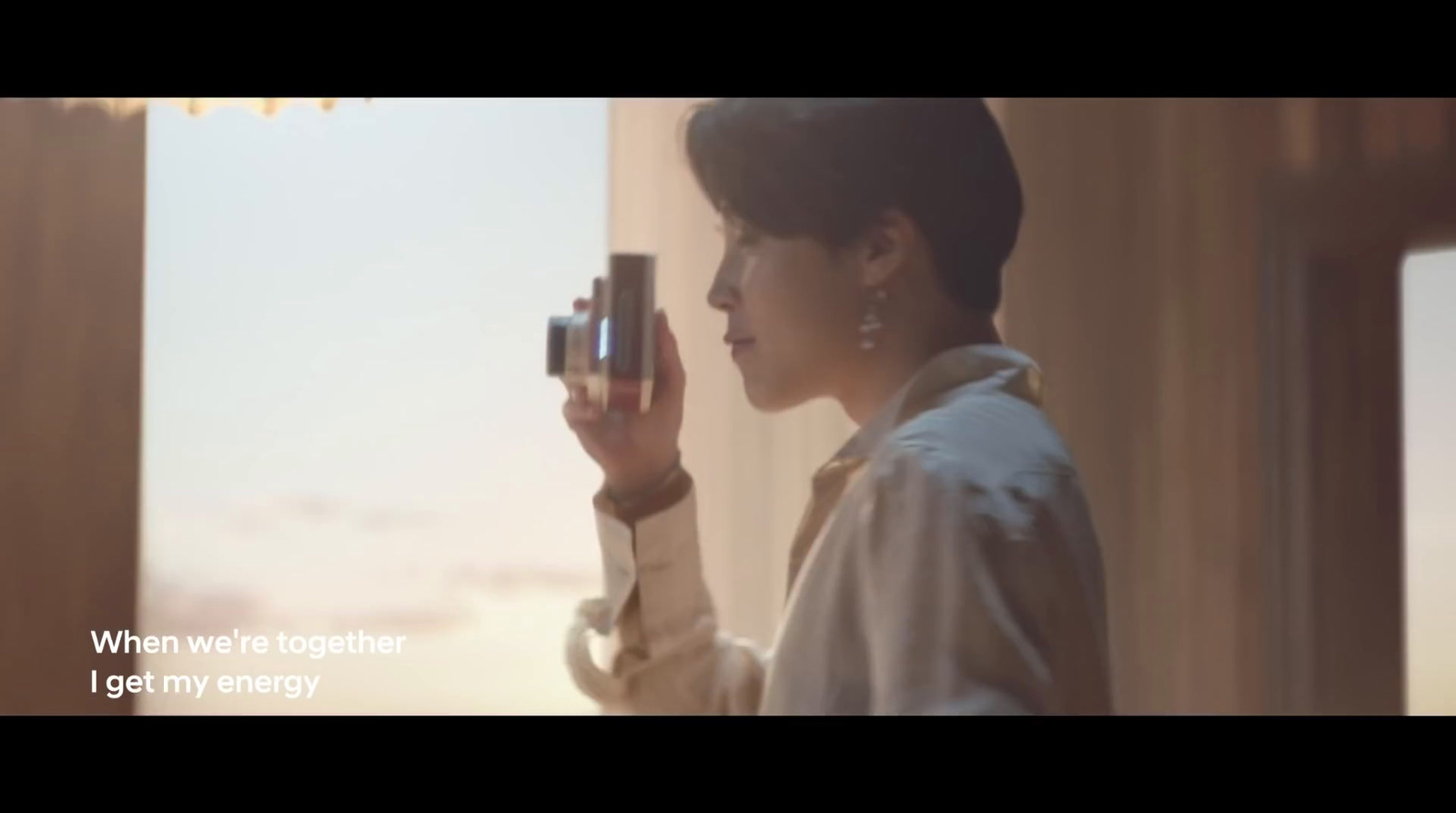 a woman looking out a window holding a camera