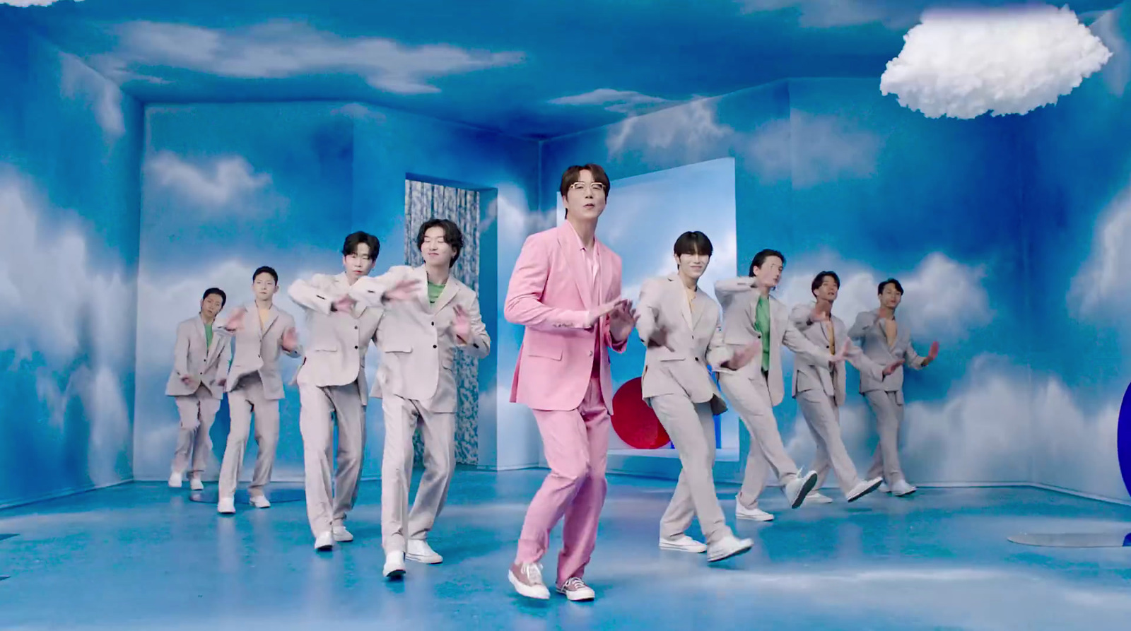 a man in a pink suit standing in front of a group of other men