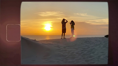 a couple of people standing on top of a sandy beach