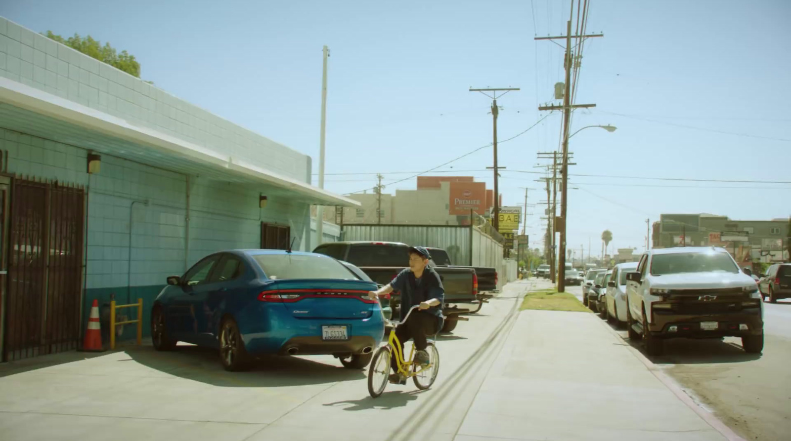 a man riding a bike down a street next to parked cars