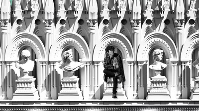 a woman sitting on a bench in front of a building