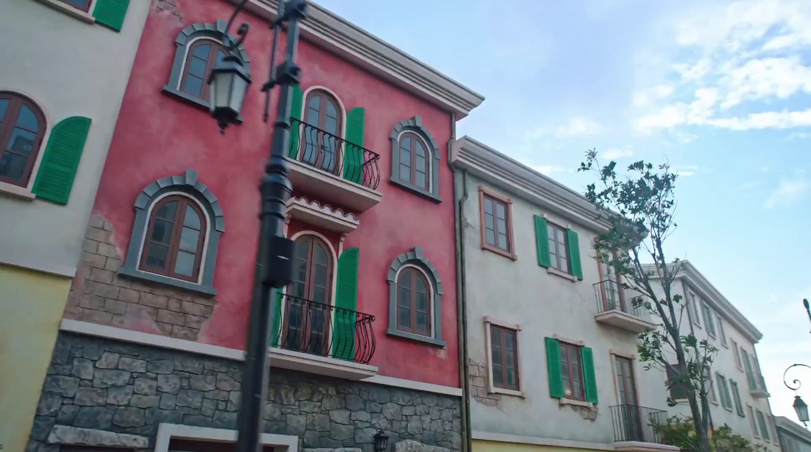 a red building with green shutters and a street light