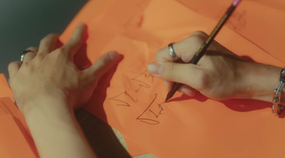 a person drawing on a piece of paper with a pencil