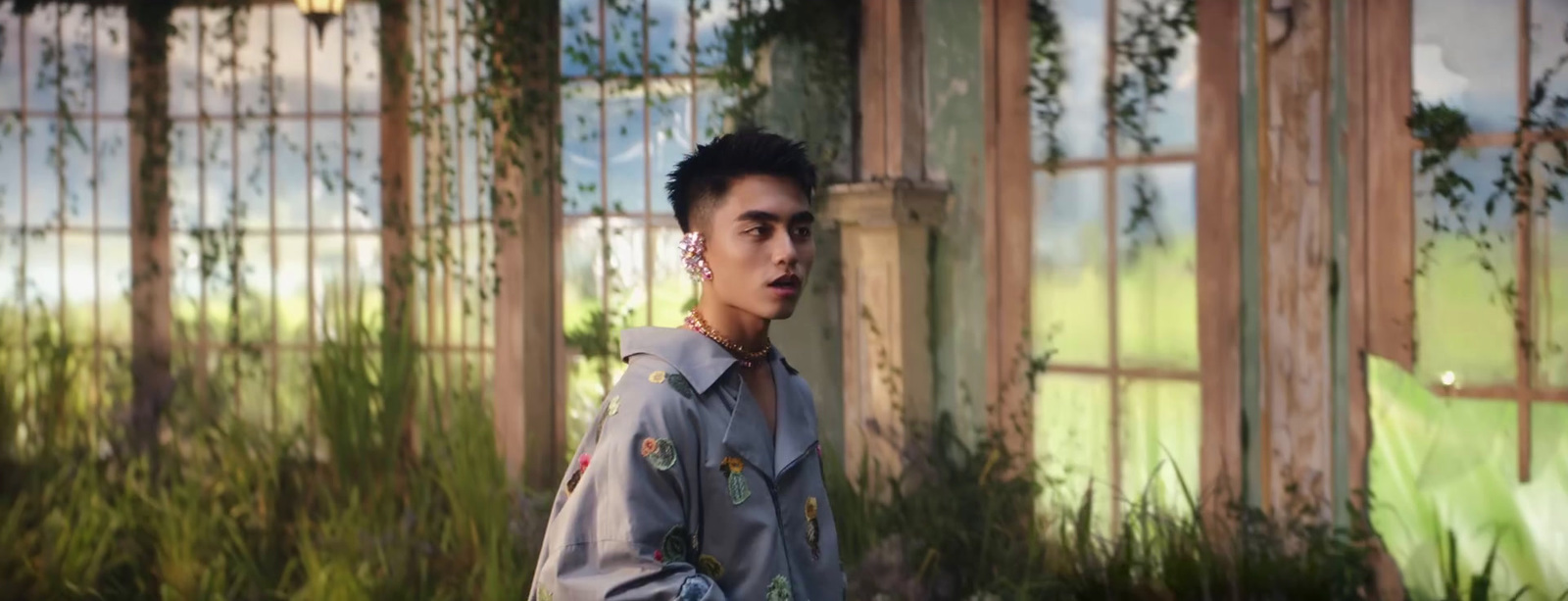 a man standing in front of a window next to plants