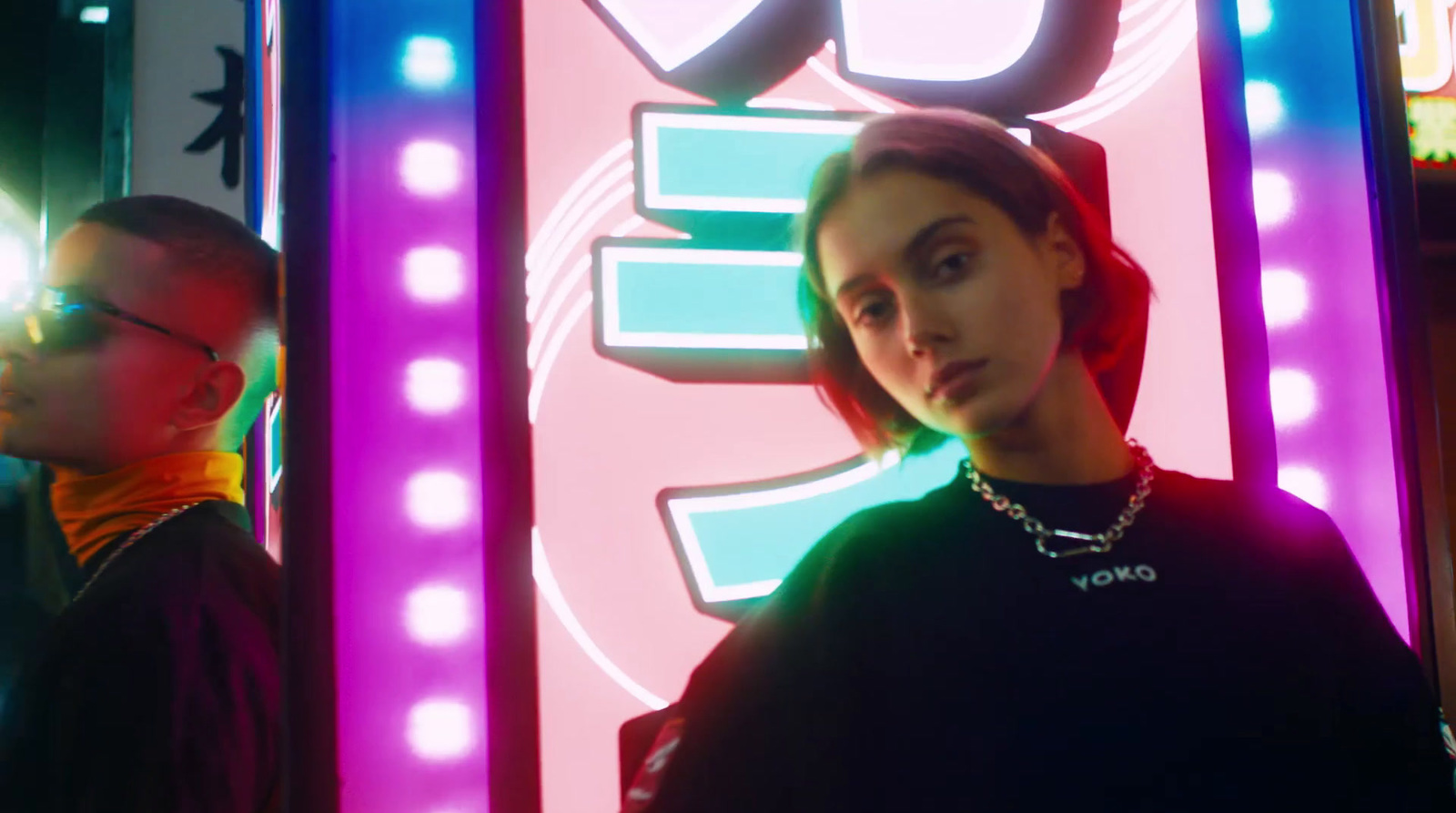 two people standing in front of a neon sign