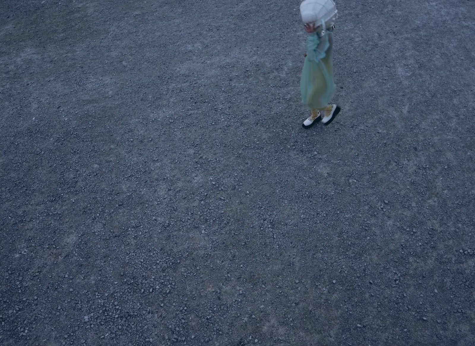 a little girl walking across a street holding an umbrella