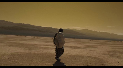 a man walking across a desert covered in dirt